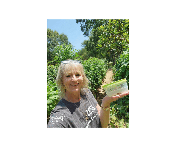 Lisa Cuevas standing in front of her vegetable garden holding a FridgeSmart Mini Hostess Reward