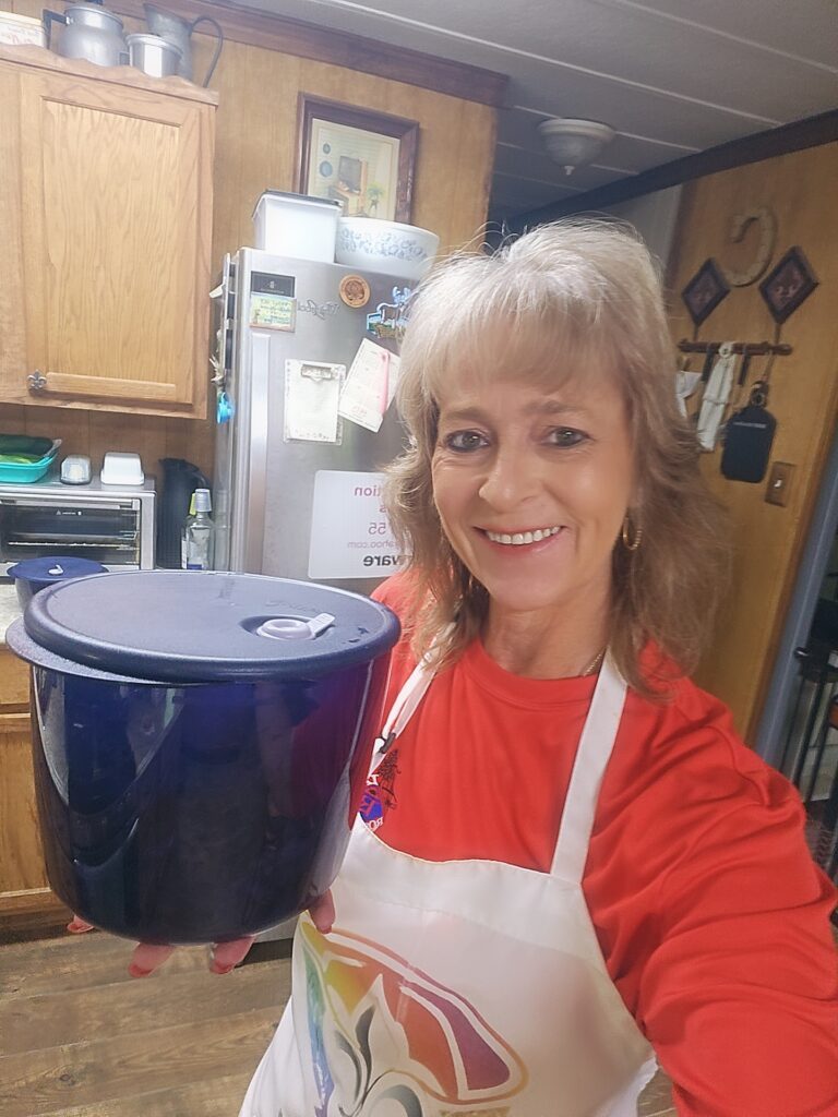 Lisa holding a blue Vent ’N Serve container in her kitchen — reusable microwave-safe container that keeps family meals fresh and warm.