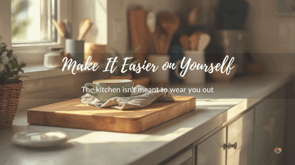 Soft, sunlit kitchen counter with a wooden cutting board, folded dish towel, and a green coffee mug near a window; blurred utensils in the background. Overlaid text reads “Make It Easier on Yourself” with the subtitle “The kitchen isn’t meant to wear you out.”