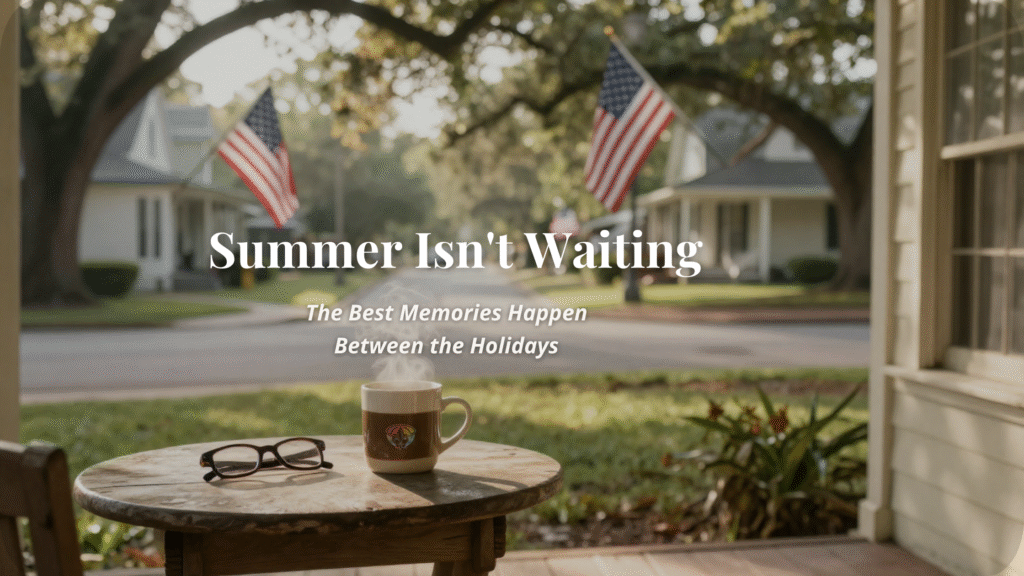 A steaming cup of coffee and reading glasses sit on a small wooden table on a front porch overlooking a peaceful neighborhood with American flags gently waving in the morning light after the Fourth of July.