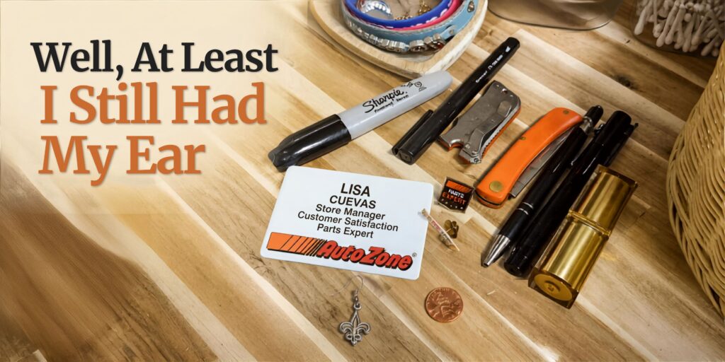 Lisa’s AutoZone badge and workday belongings beside one remaining fleur-de-lis earring, illustrating the story “Well, At Least I Still Had My Ear.”