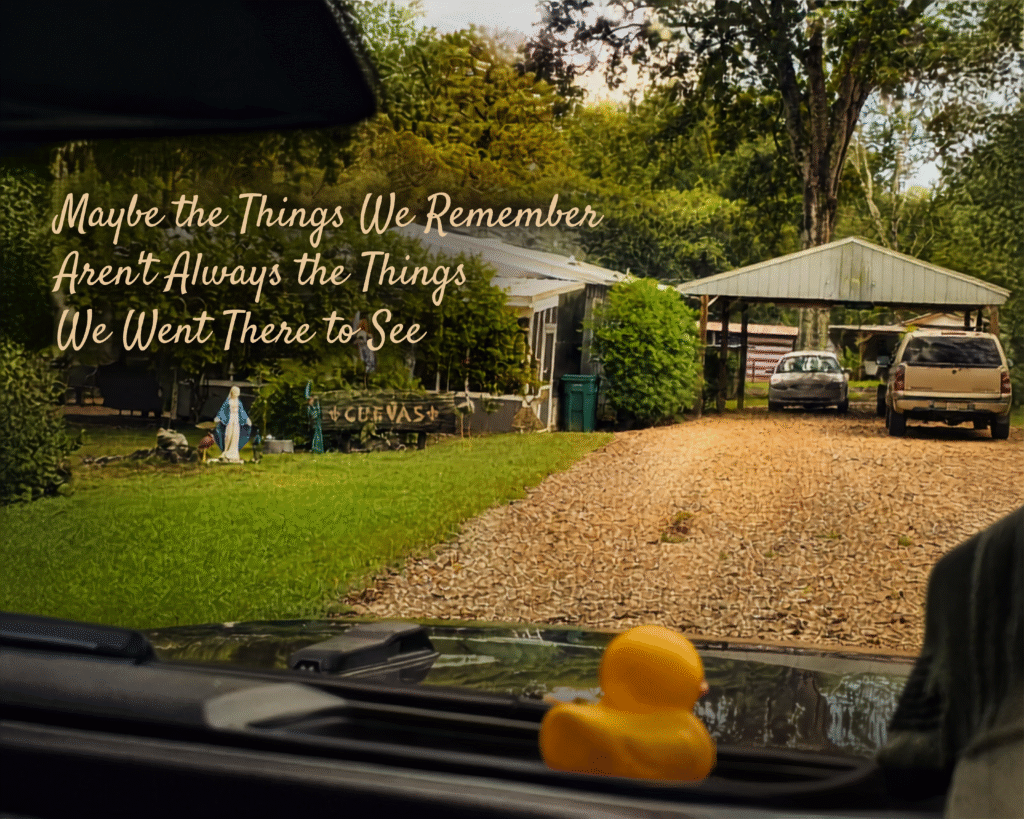View through Mabel’s windshield arriving home after vacation, with a yellow rubber duck on the dashboard and the Cuevas driveway and home ahead.